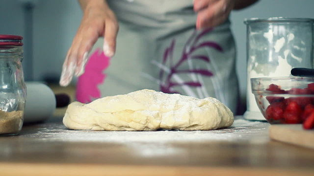 Female hands in flour kneading dough on table, slow motion
