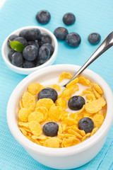 bowl of cornflakes with milk and blueberries