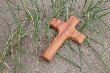 Holzkreuz am Strand unter Gräsern