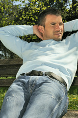 Obraz premium attractive man is relaxing on a bench in a natural environement