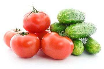 Fresh raw tomatoes and cucumbers over a white background.