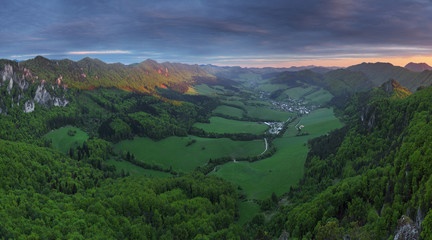 Green forest mountain at sunset with sun