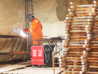 Worker in orange clothes weld metal gratings