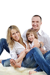 Father embraces daughter and wife sitting on carpet
