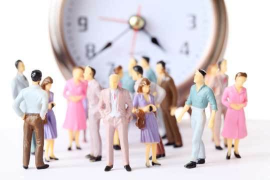 miniature toy people stand in different poses near alarm clock