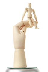 wooden mannequin sitting on big wooden hand isolated on white