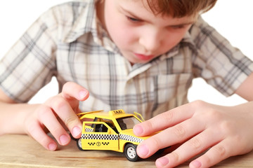 little boy in plaid shirt playing with toy yellow Taxi isolated