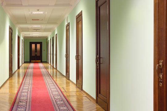 long hallway with brown wood doors, door at end of corridor
