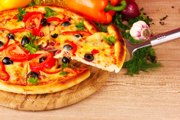 pizza and vegetables on wooden background