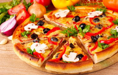 pizza and vegetables on wooden background