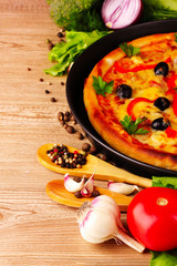 pizza and vegetables on a wooden background