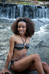 Pretty woman sitting in swim suit by a stream of clean water