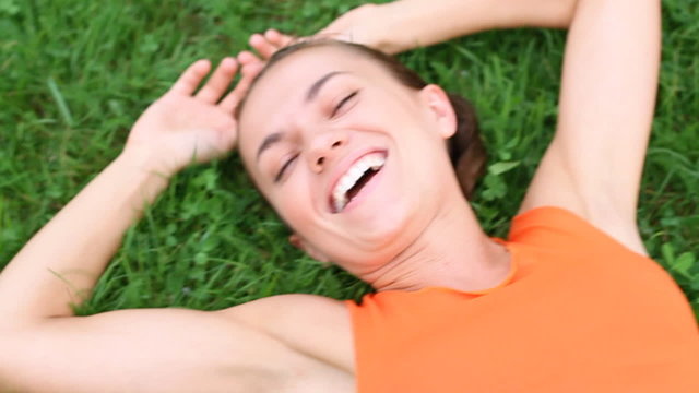 Young happy woman lying on the grass, top view, slow motion