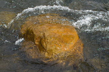 Water surrounding a rock in the river