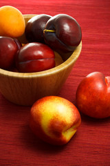 Fototapeta na wymiar Juicy nectarines, plums and apricots on red background