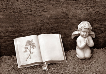 Engelsskulptur und Buch auf Friedhof