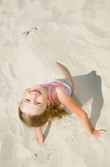 Little girl buried in the sand of the beach
