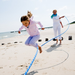 Family playing with skipping rope at the beach