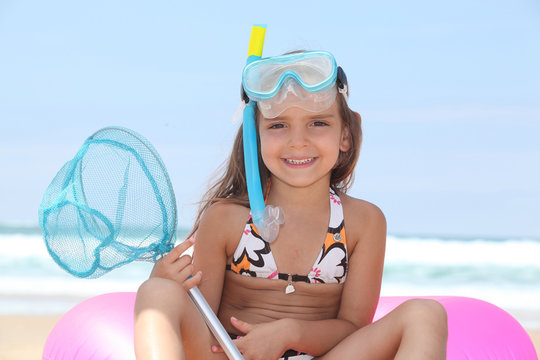 Young girl on the beach with snorkel, mask and fishing net - Powered by Adobe