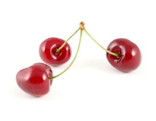 Three cherries against a white background