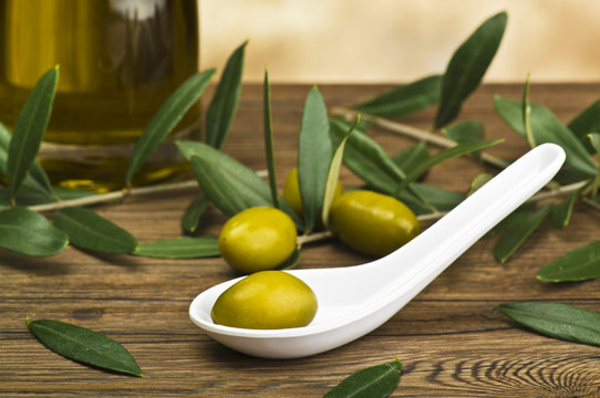 green olives in spoon whit bottle and leaf.