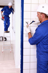 an electrician screwing an electrical outlet