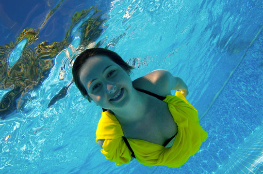 Attractive young girl diving at swimming pool.