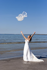 Fototapeta na wymiar beautiful young bride throwing the veil near the sea