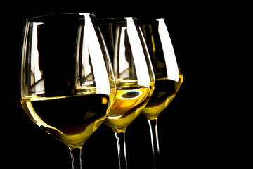 three glasses of white wine on black background