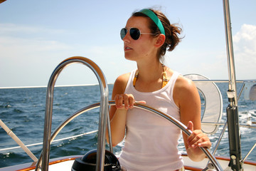 Pretty young woman steering sailboat