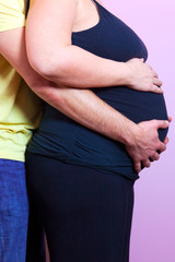 Pregant woman with husband both holding the baby