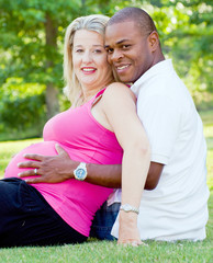 Portrait of mixed race couple outdoors with pregnant mom