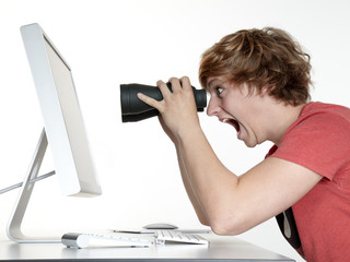 Shocked man at work searching with spyglass on the internet
