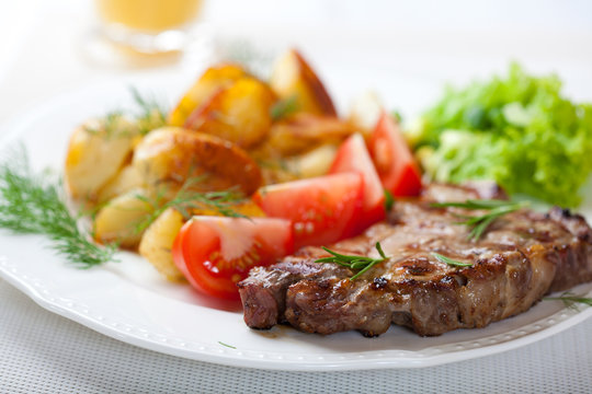 Grilled steak with baked potatoes and fresh vegetables