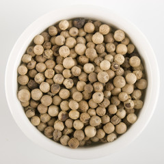 Ciotola di pepe bianco in grani su sfondo bianco dall'alto