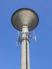 Concrete water tower on clear blue sky, vertical view