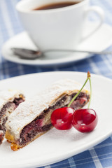 Poppy seed strudel with cherry and cup of coffee or tea.