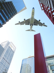 Fototapeta na wymiar Airplane flying over high buildings