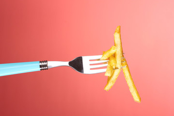 French fries and fork on red background