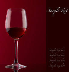 Glass with red wine on a red background