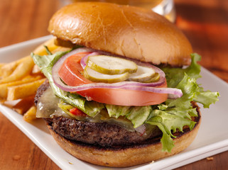 gourmet cheeseburger with mug of beer in background