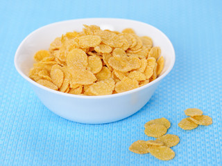 Cornflakes in porcelain bowl on a blue background