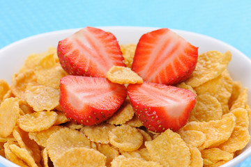 Cornflakes in porcelain bowl with cut strawberry