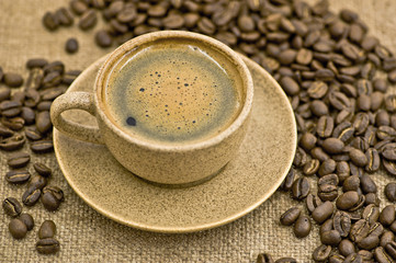 Чашка кофе с кофейными зернами на мешковине