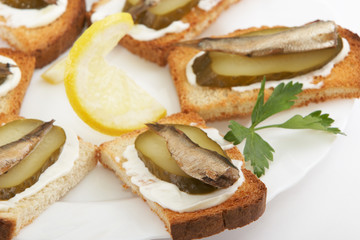 Sandwiches with sprats on a white plate