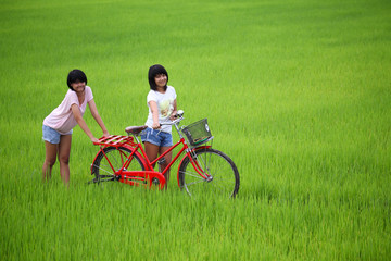 Fototapeta premium Two girls having fun on bike in paddy field