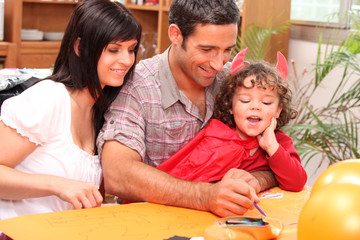 Girl dressed in a devil's costume together with her parents