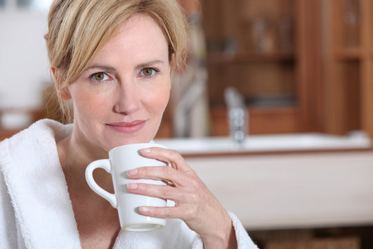Blond woman in dressing gown drinking coffee