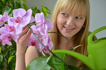 Junge Frau gießt Orchideen