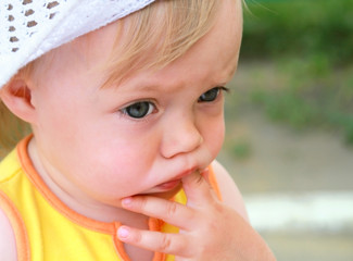 Portrait of the little girl with fingers in a mouth